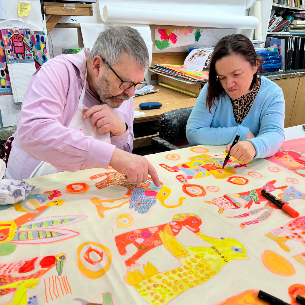 Two people working on a colorful art project at a table.