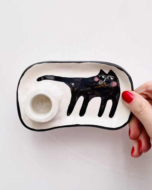 Ceramic tray with a black cat design held by a hand on a white background