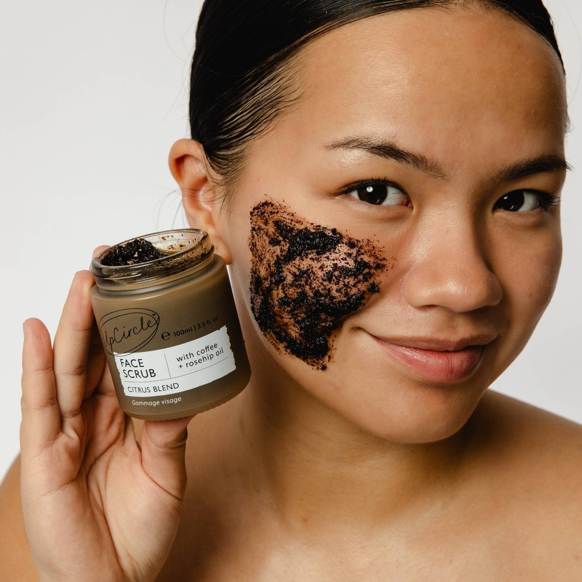 A model applying the citrus blend face scrub onto their face.