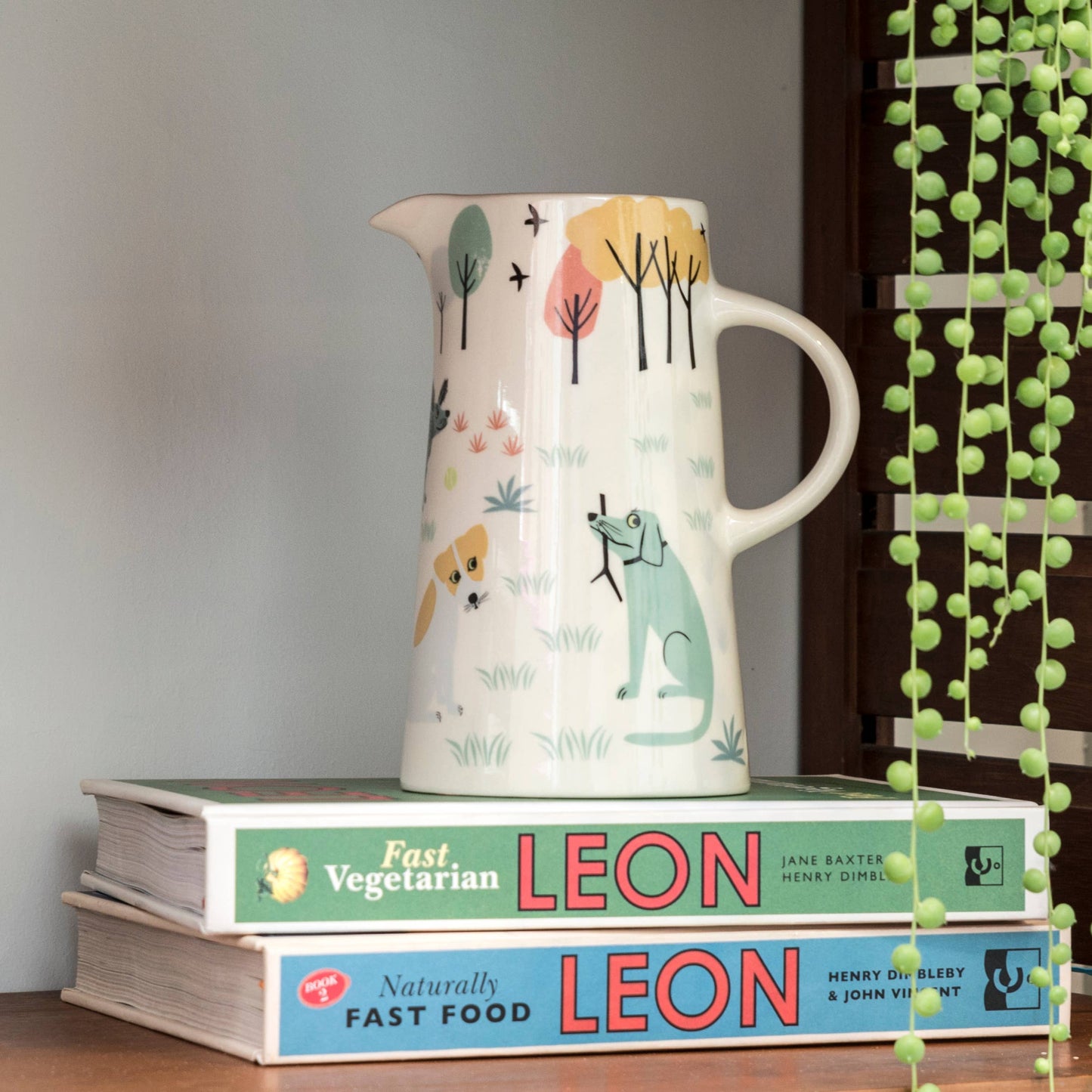Ceramic pitcher with dog design on a stack of books with visible text