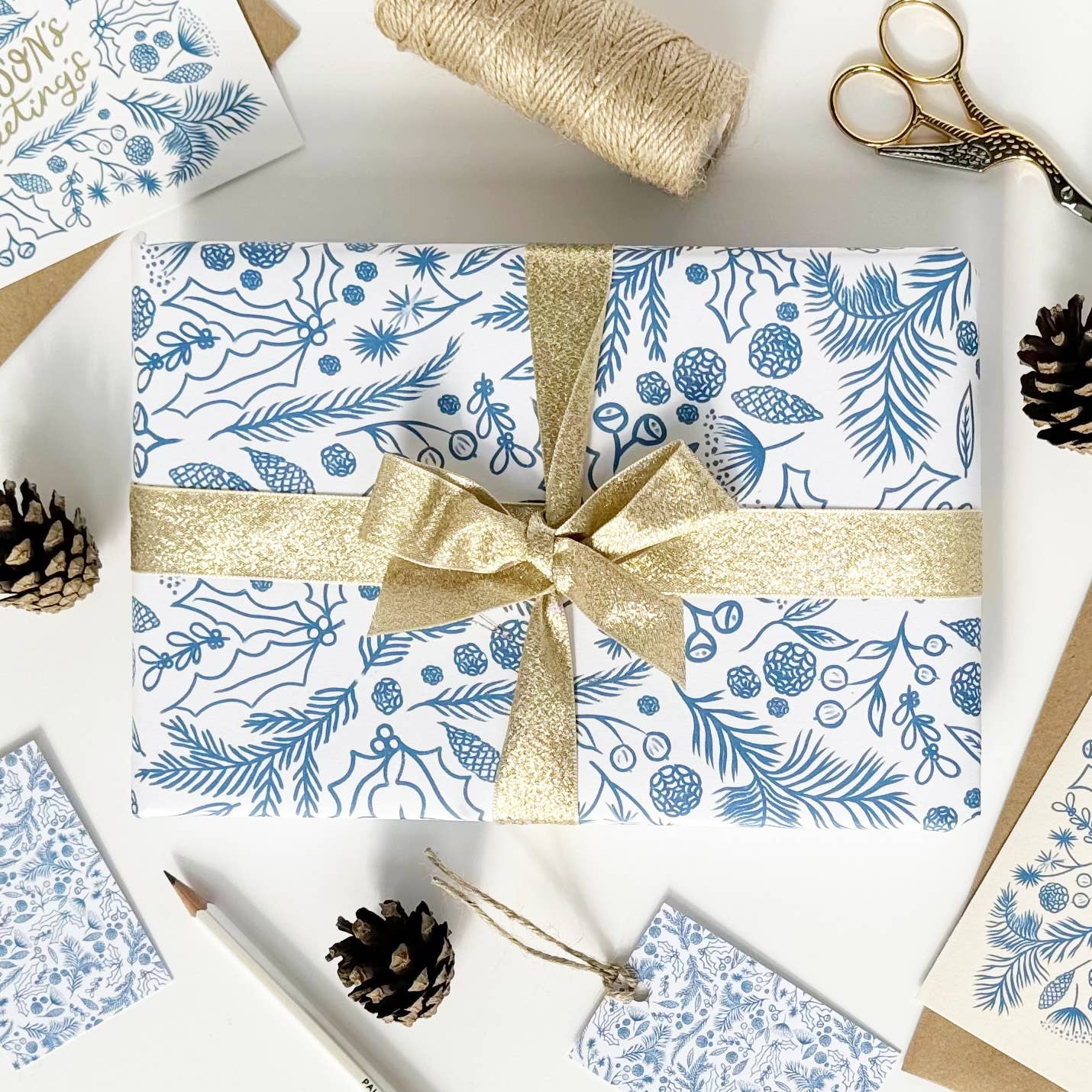 Blue on white gift wrap with festive foliage drawings.