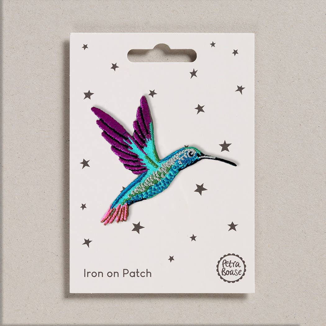 Colorful hummingbird iron on patch on a white card with star patterns.