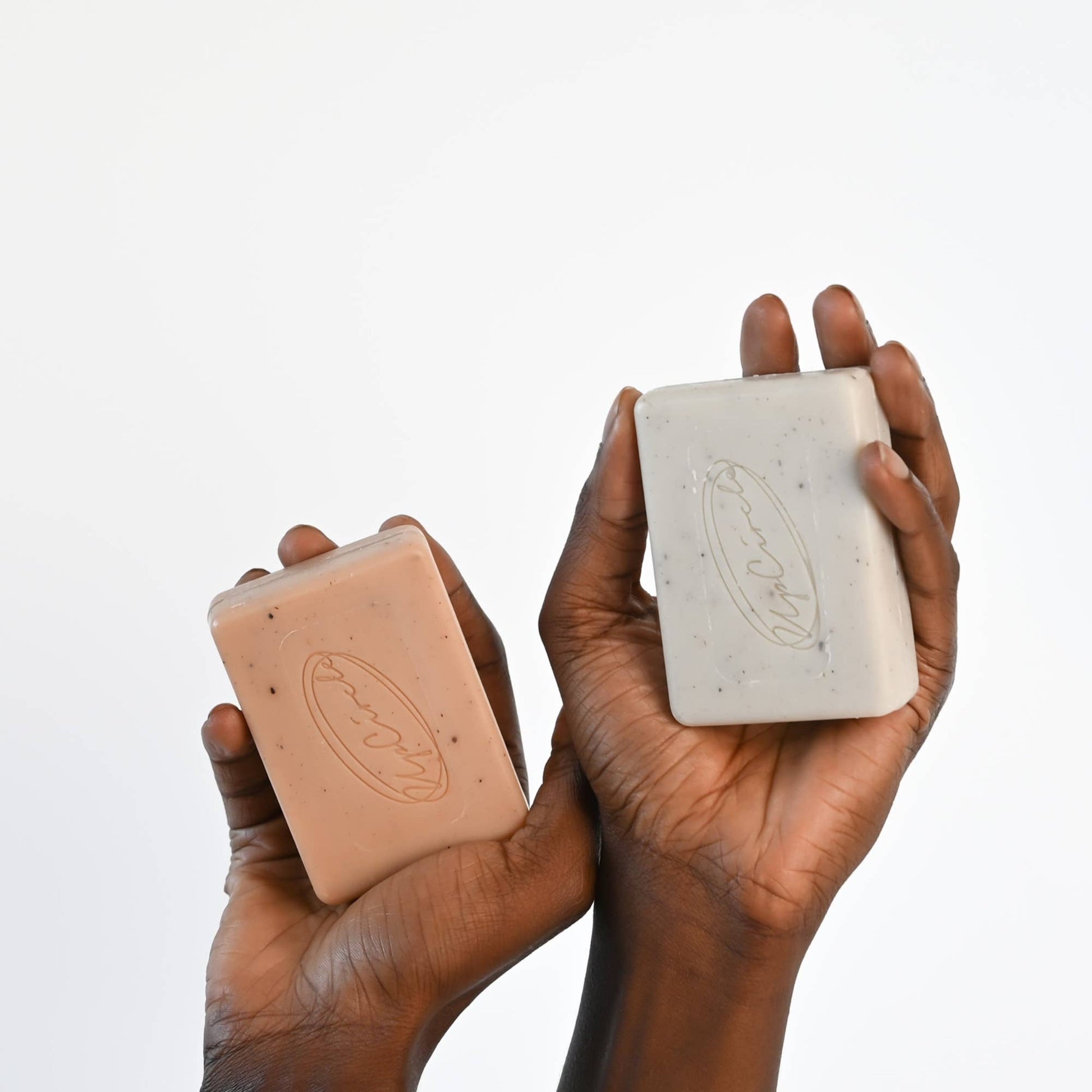Two hands holding bars of soap against a white background