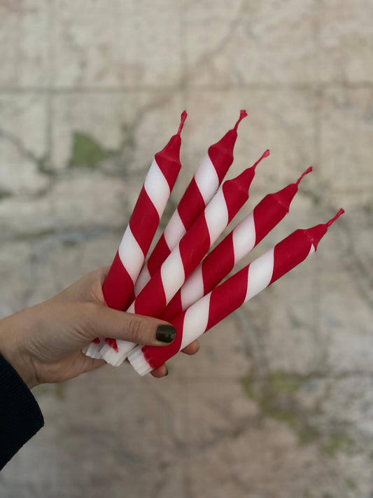 Hand holding red and white striped candles against a blurred background