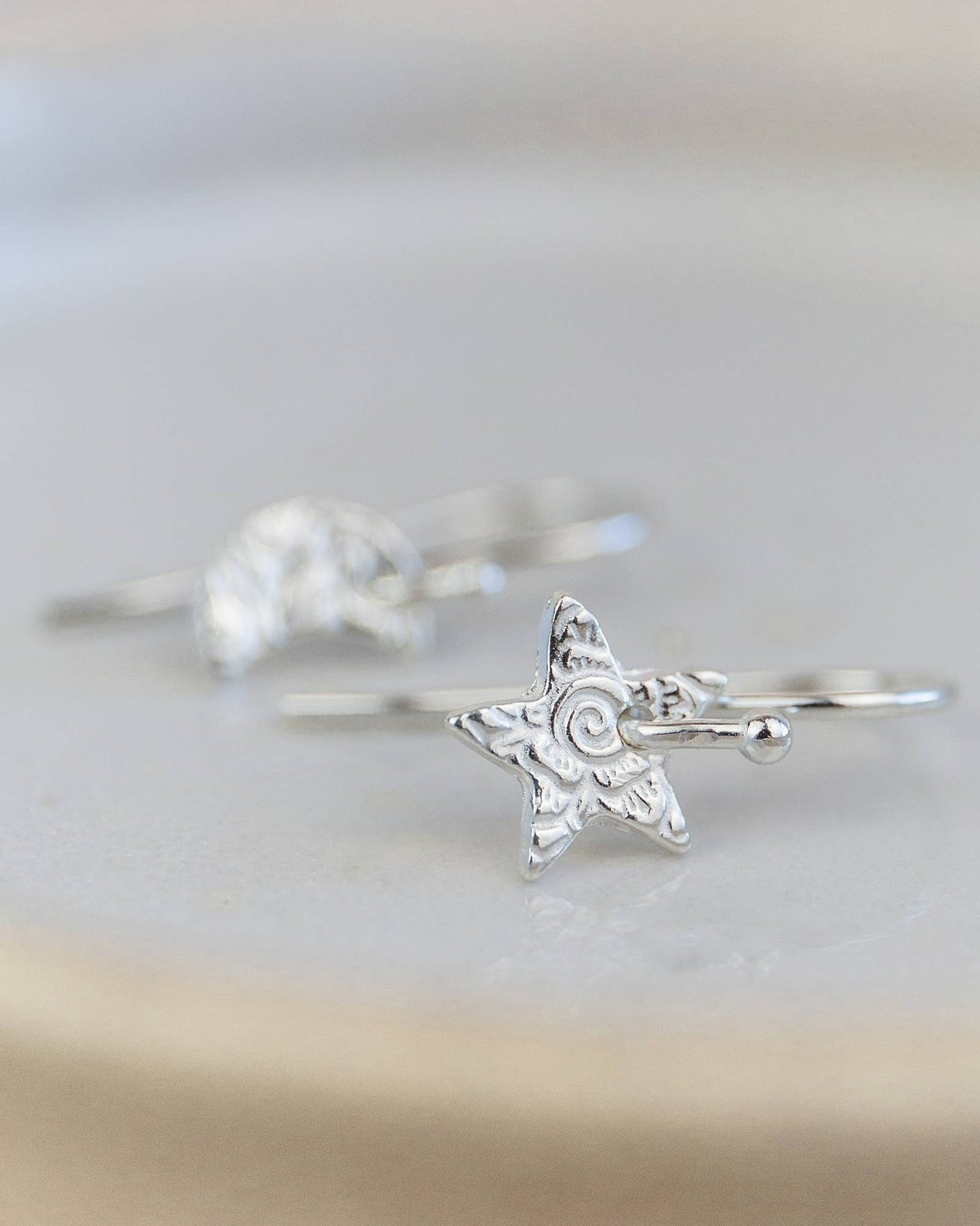 Silver star-shaped ring on a light gray background