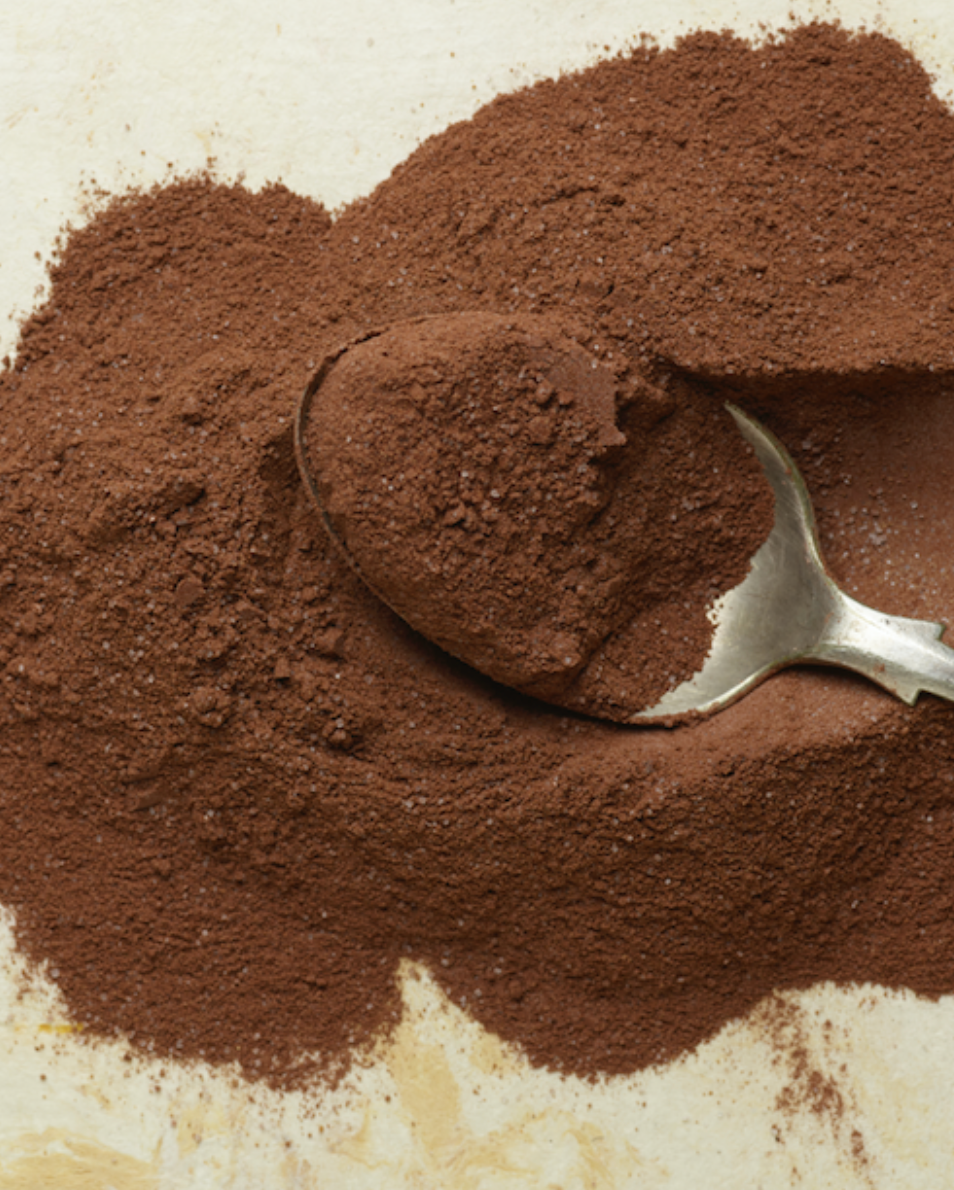 Cocoa powder with a spoon on a textured surface