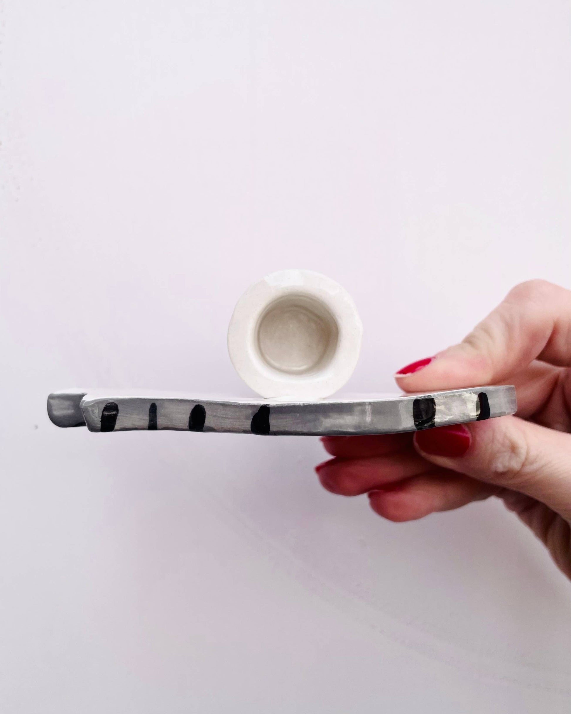 Hand holding a ceramic pipe with a white background