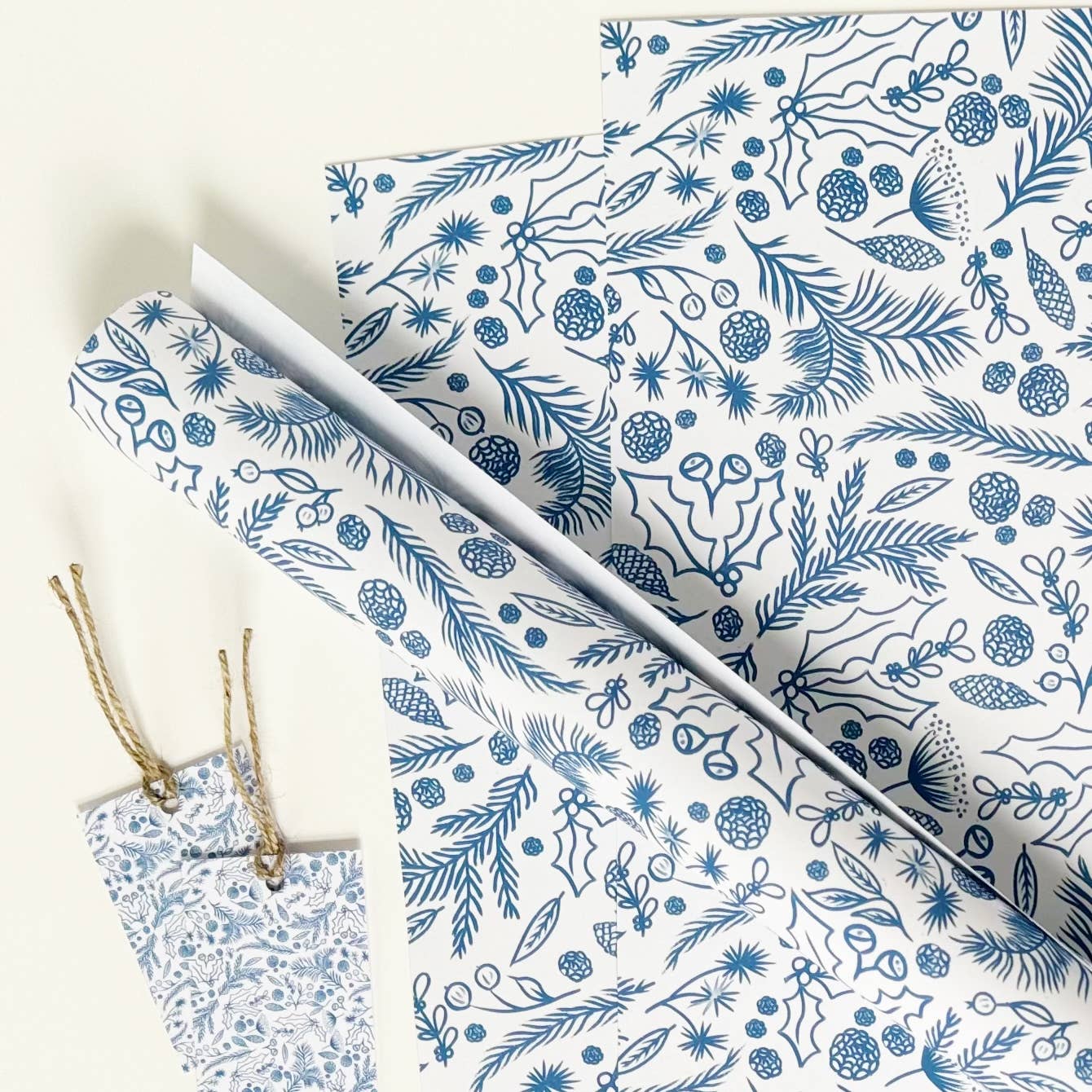 Blue on white gift wrap with festive foliage drawings.