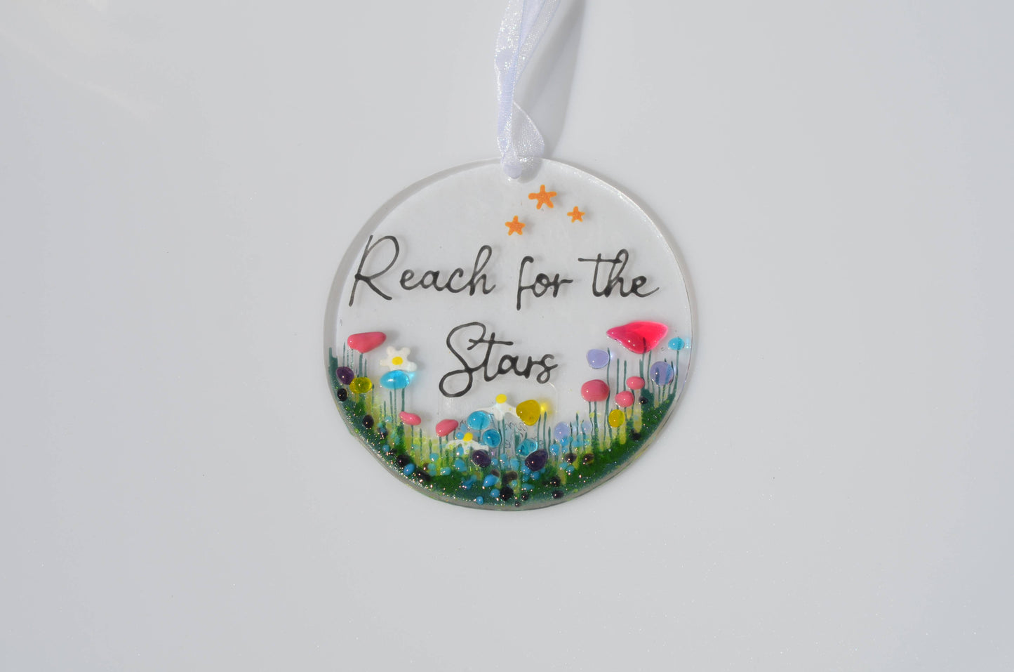 Decorative hanging disc with floral design and 'Reach for the Stars' text on a white background