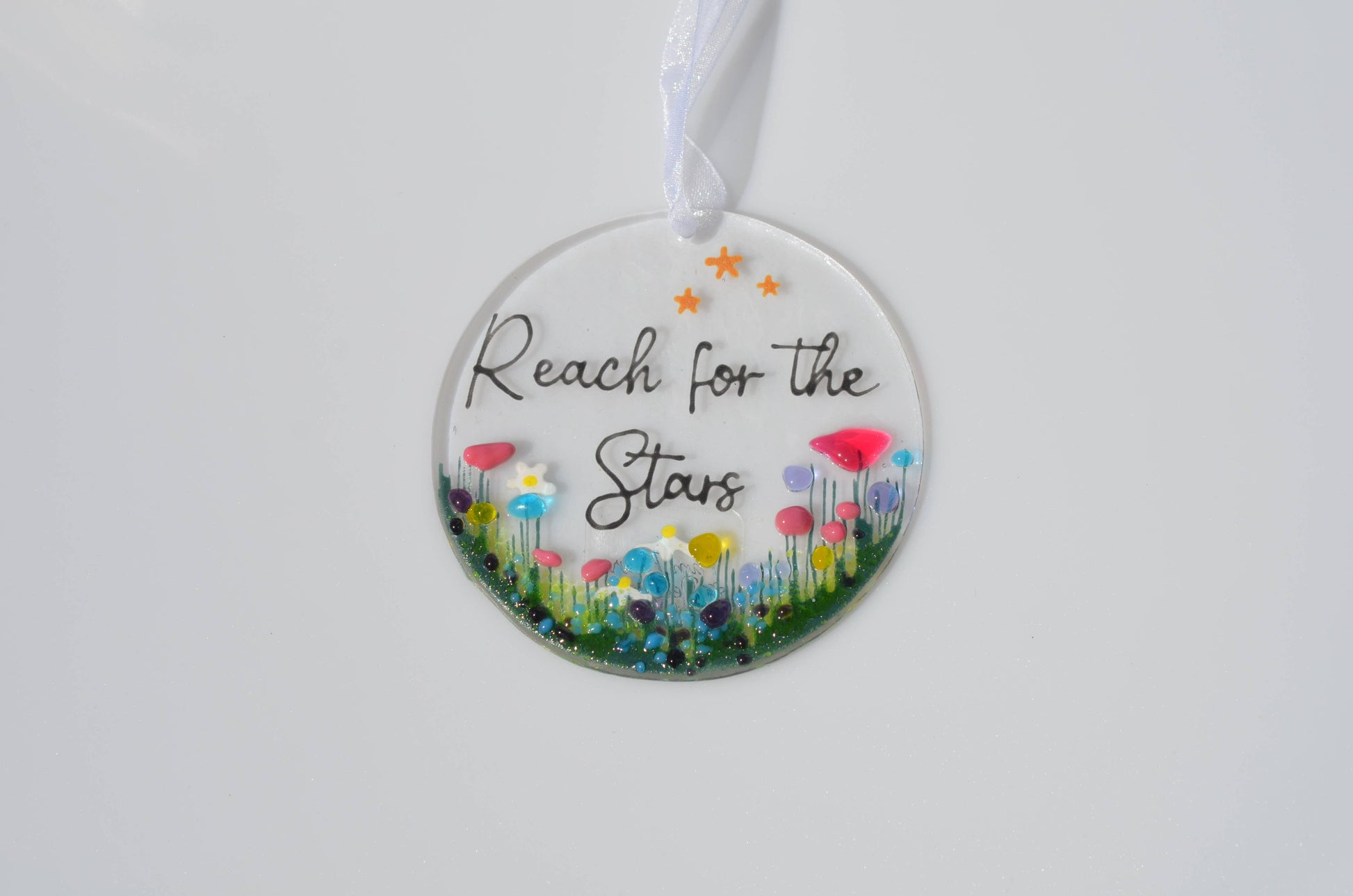 Decorative hanging disc with floral design and 'Reach for the Stars' text on a white background