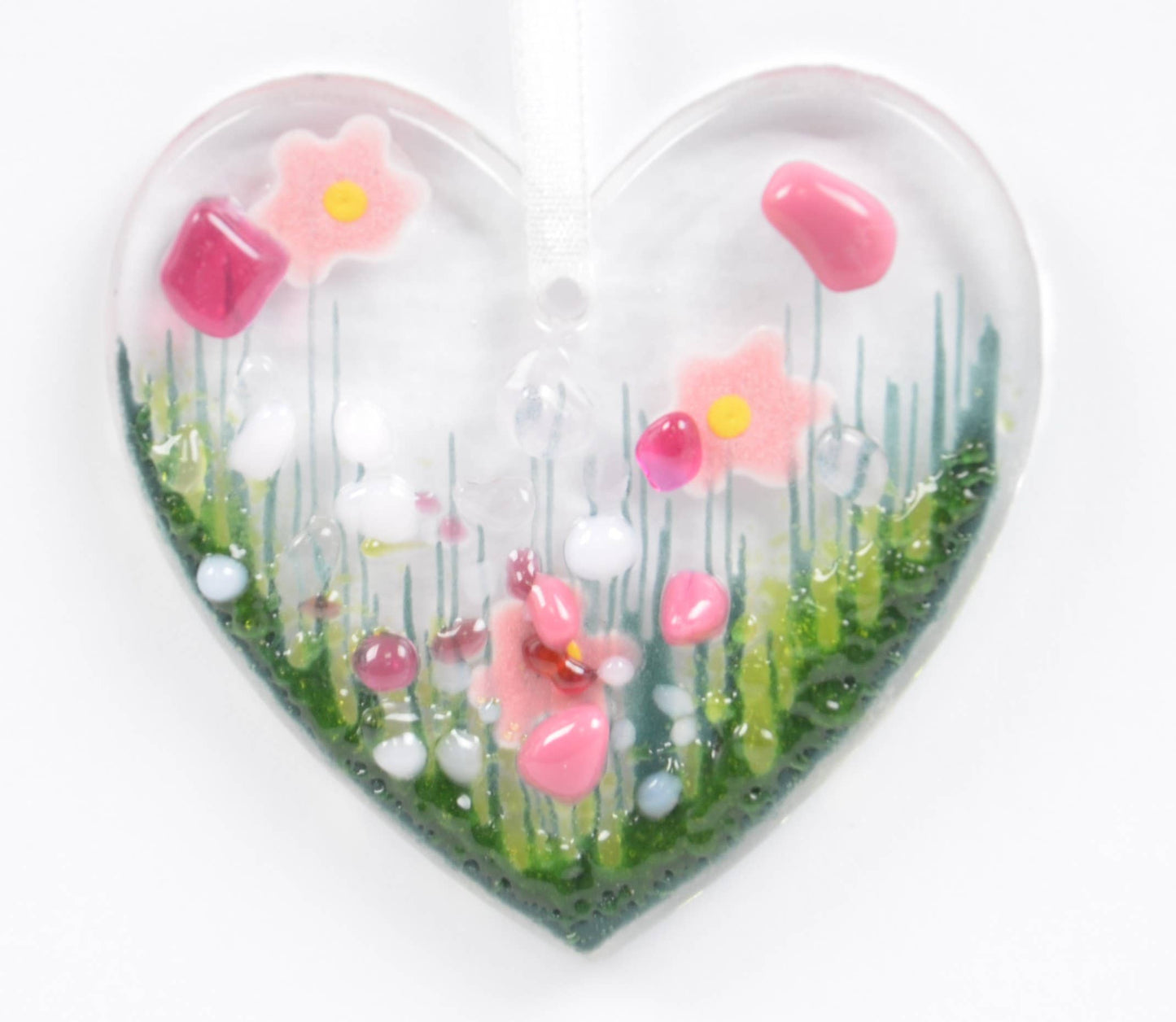 Heart-shaped object with pink flowers and a small figure on a white background