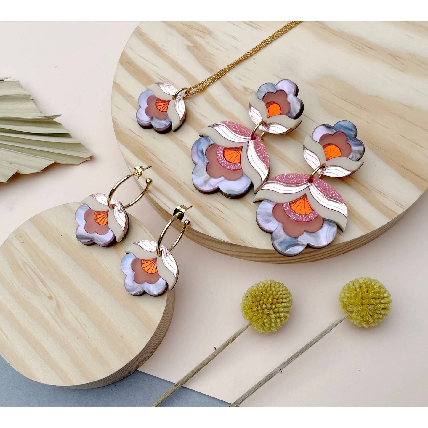 Floral-themed jewelry set on a wooden surface with decorative elements.
