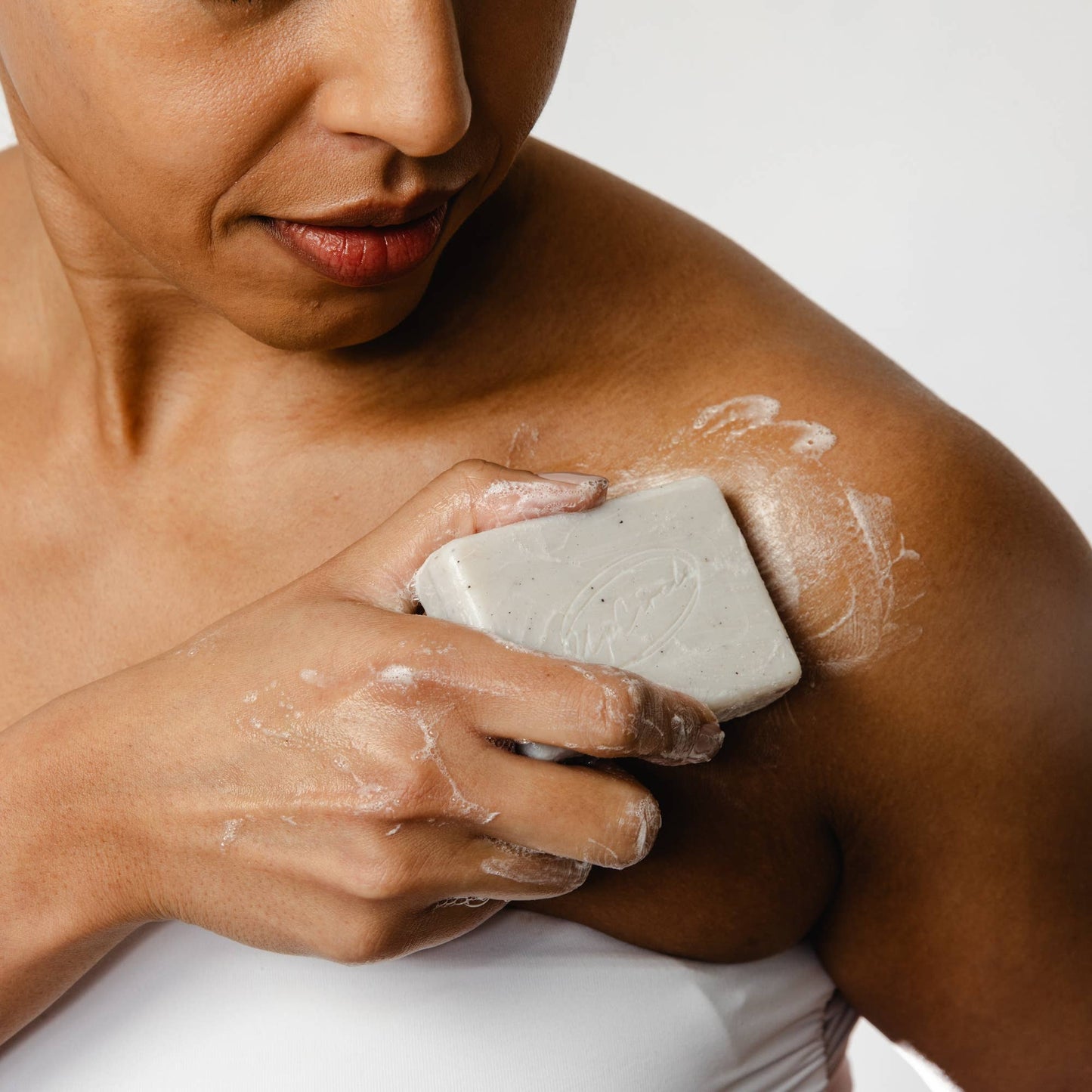Person applying soap to their shoulder with a bar of soap.