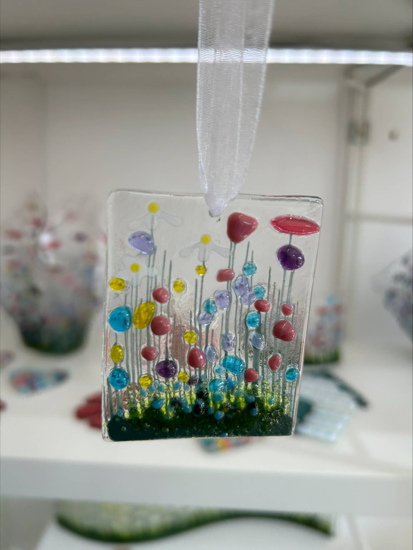 handmade fused glass hanging token with floral motif.