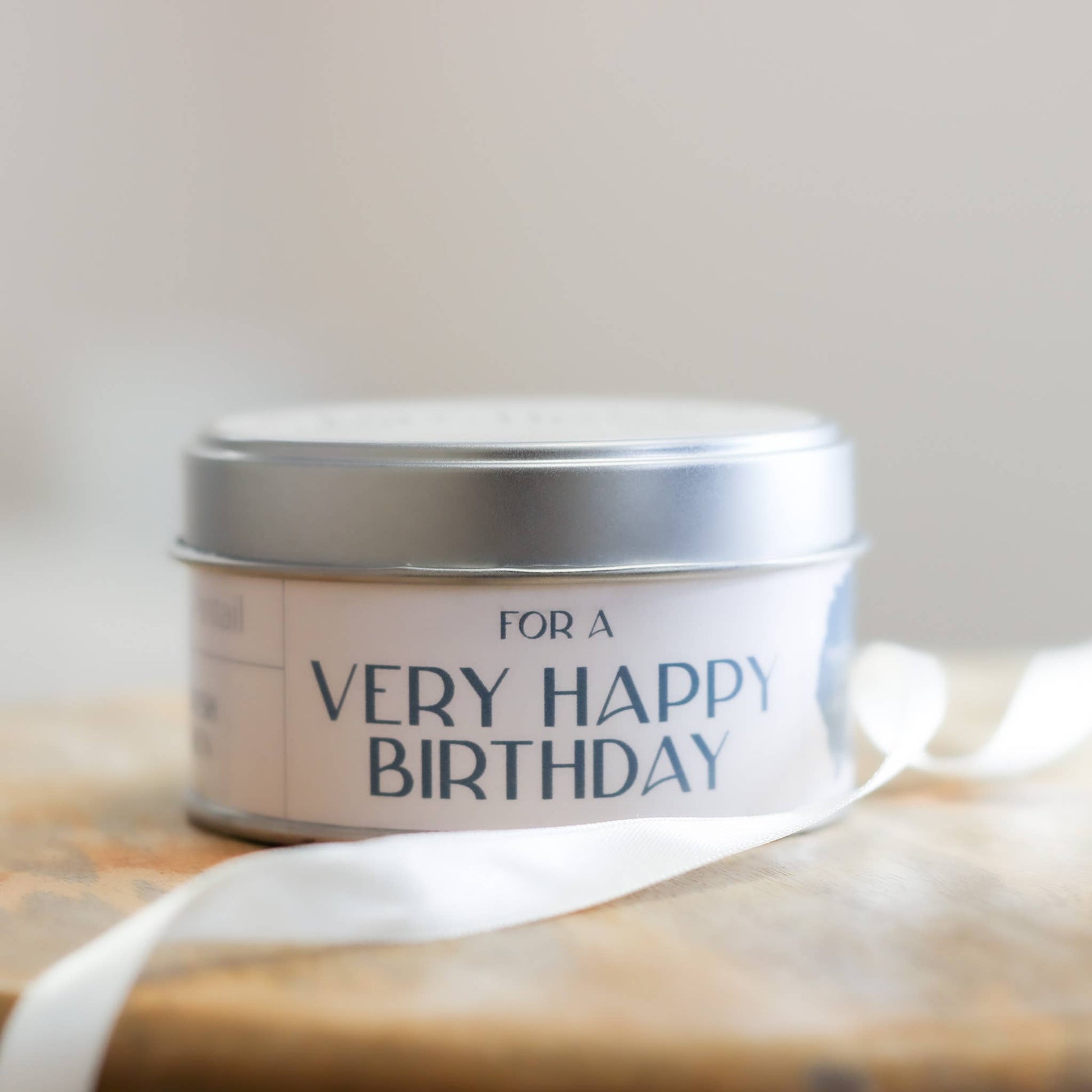 Silver tin with 'For a Very Happy Birthday' text on a wooden surface