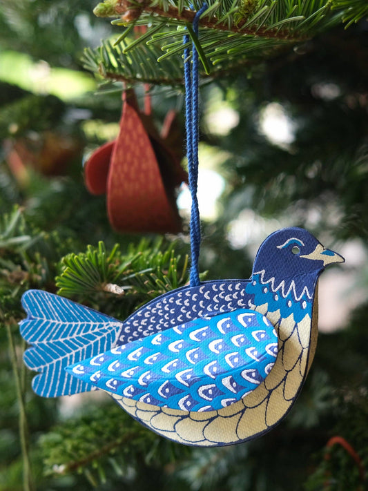 Decorative blue and white bird ornament hanging on a Christmas tree.