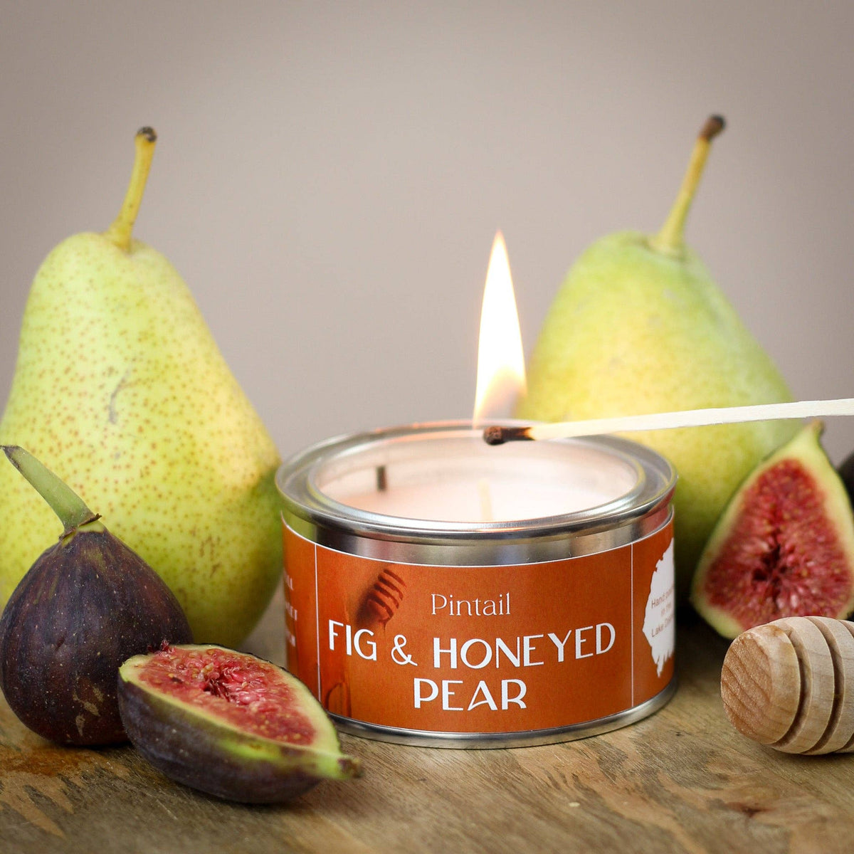 Candle labeled 'Fig & Honeyed Pear' with pears and figs on a wooden surface