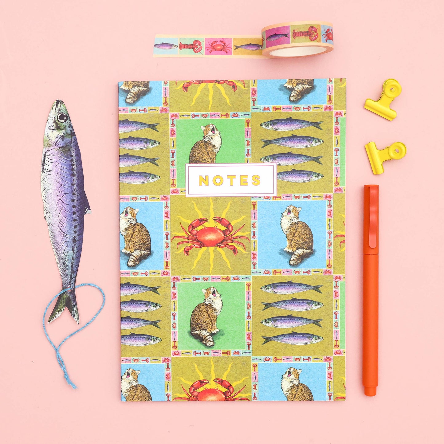 Notebook with colorful animal illustrations on a pink background, surrounded by stationery items.