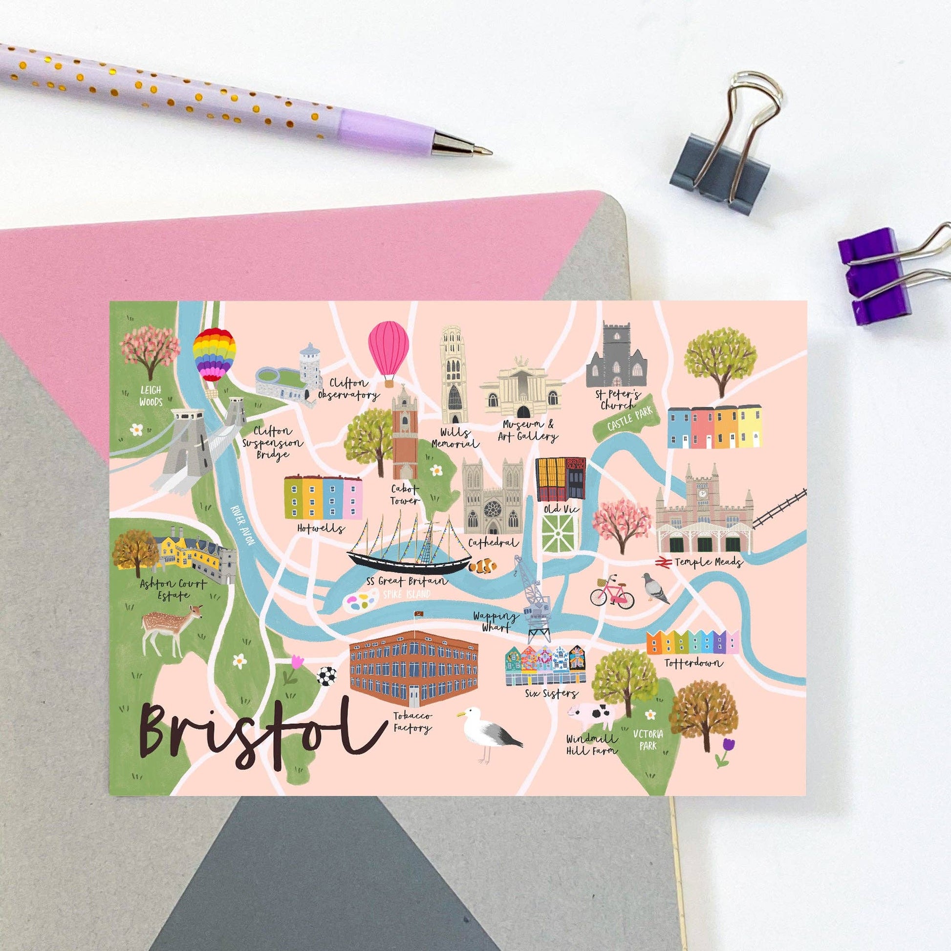 Colorful map of Bristol on a pink card with stationery items on a white background