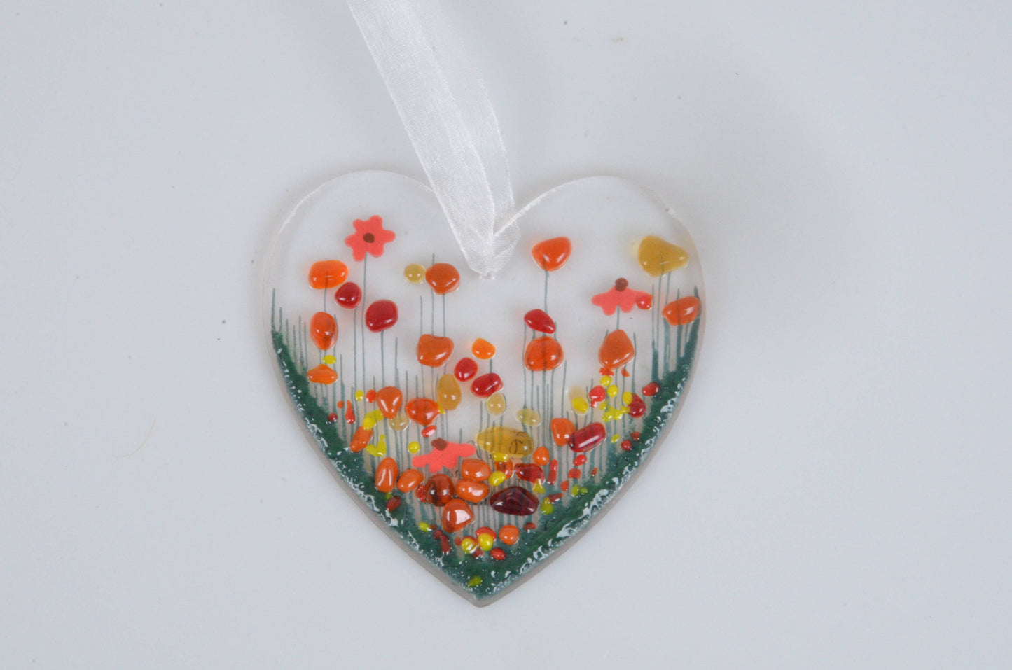 Heart-shaped glass ornament with colorful floral design on a white background