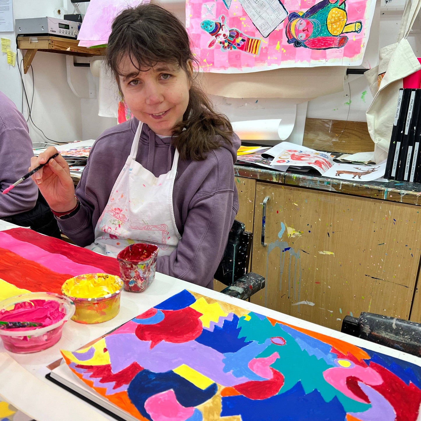 Person painting a colorful abstract artwork in an art studio.