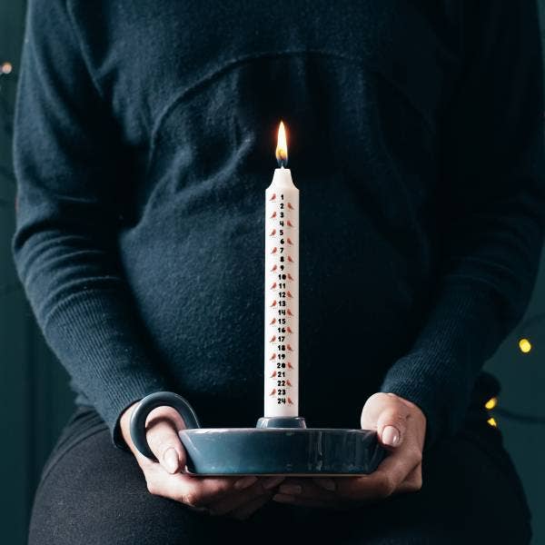 Person holding a lit candle in a dark setting