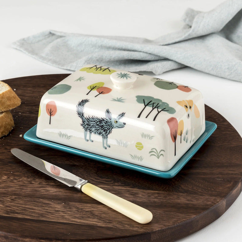 Butter dish in white with folk art style design of dogs and trees