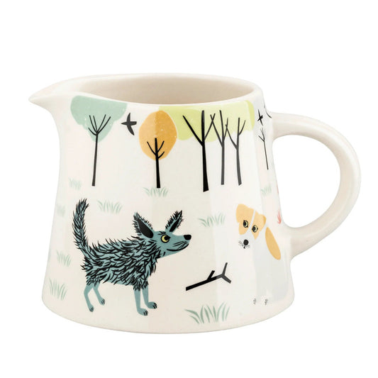 White milk jug with folk art style dog illustration with trees in background