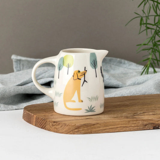 Small ceramic jug with brown dog with a stick in mouth surrounded by trees