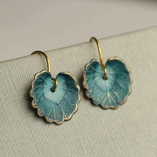 Pair of blue leaf-shaped earrings on a light gray surface