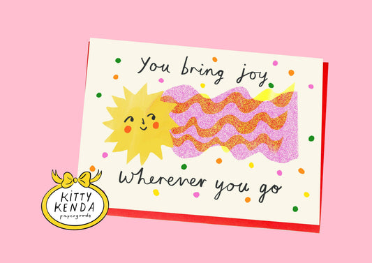 Card with sun illustration and text 'You bring joy wherever you go' on a pink background, featuring the Kitty Kenda logo.
