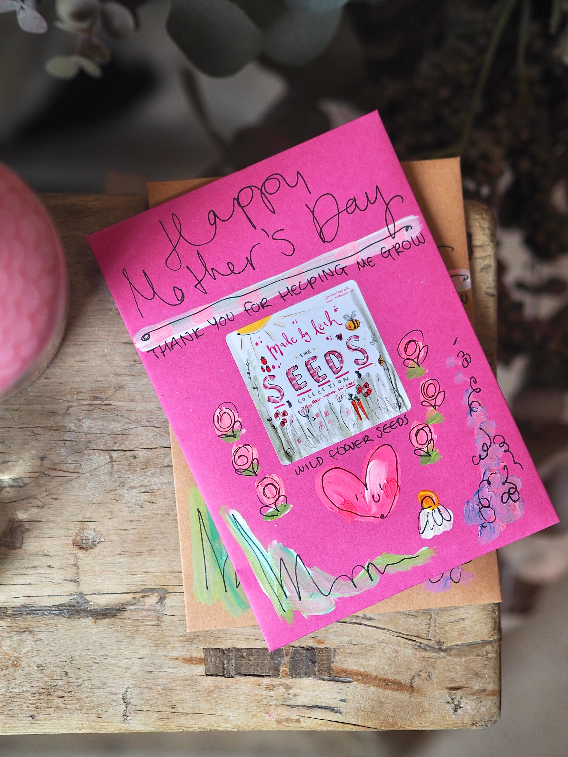 Pink Mother's Day card with garden-themed design on a wooden surface