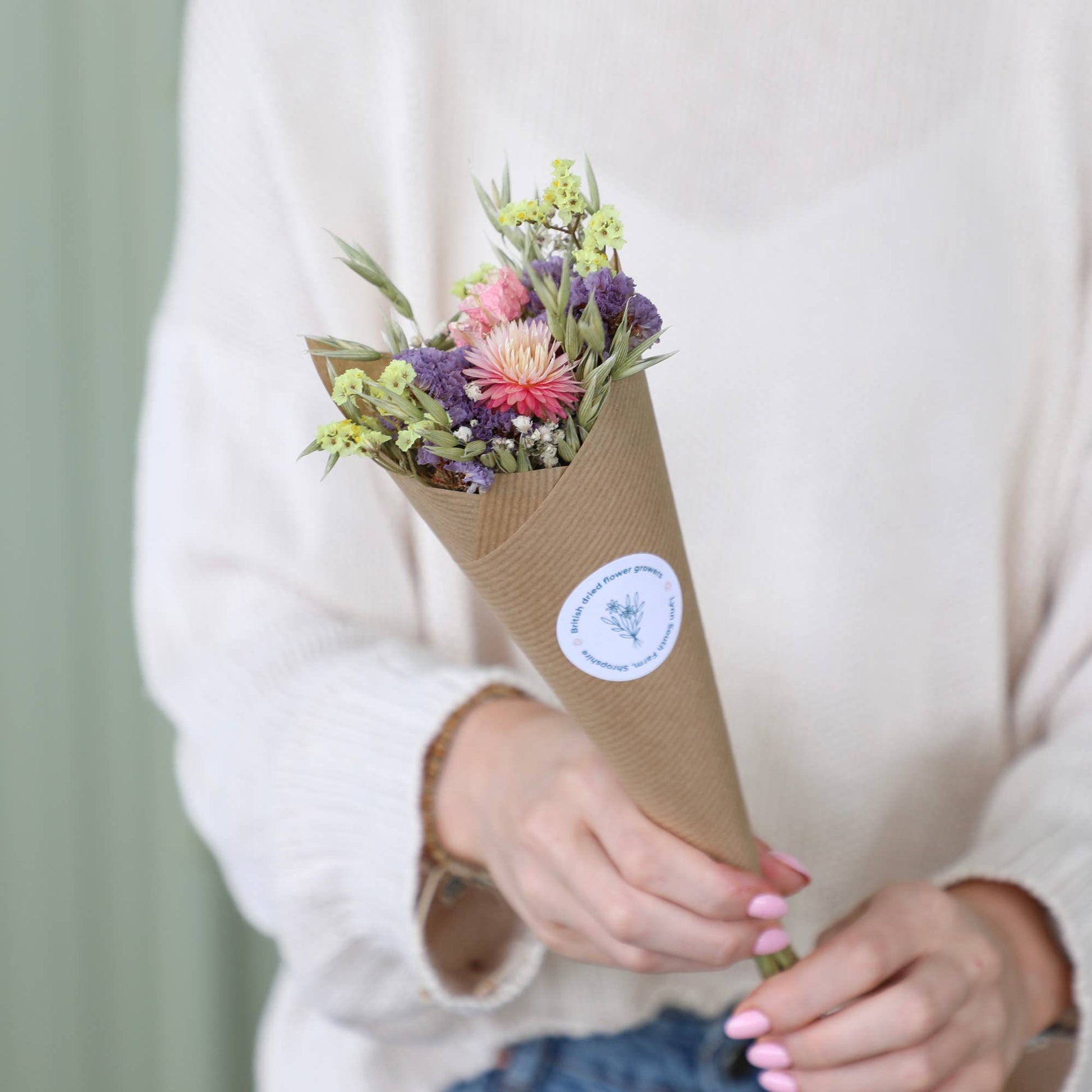 Bouquet of flowers wrapped in brown paper held by a person with a blurred background
