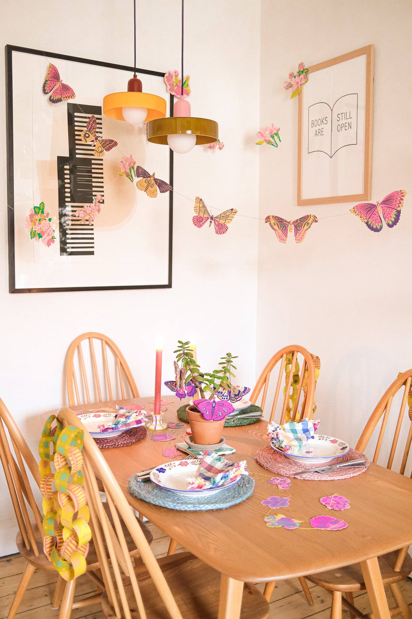 Dining room with wooden table and chairs, colorful decorations, and framed artwork on the wall.