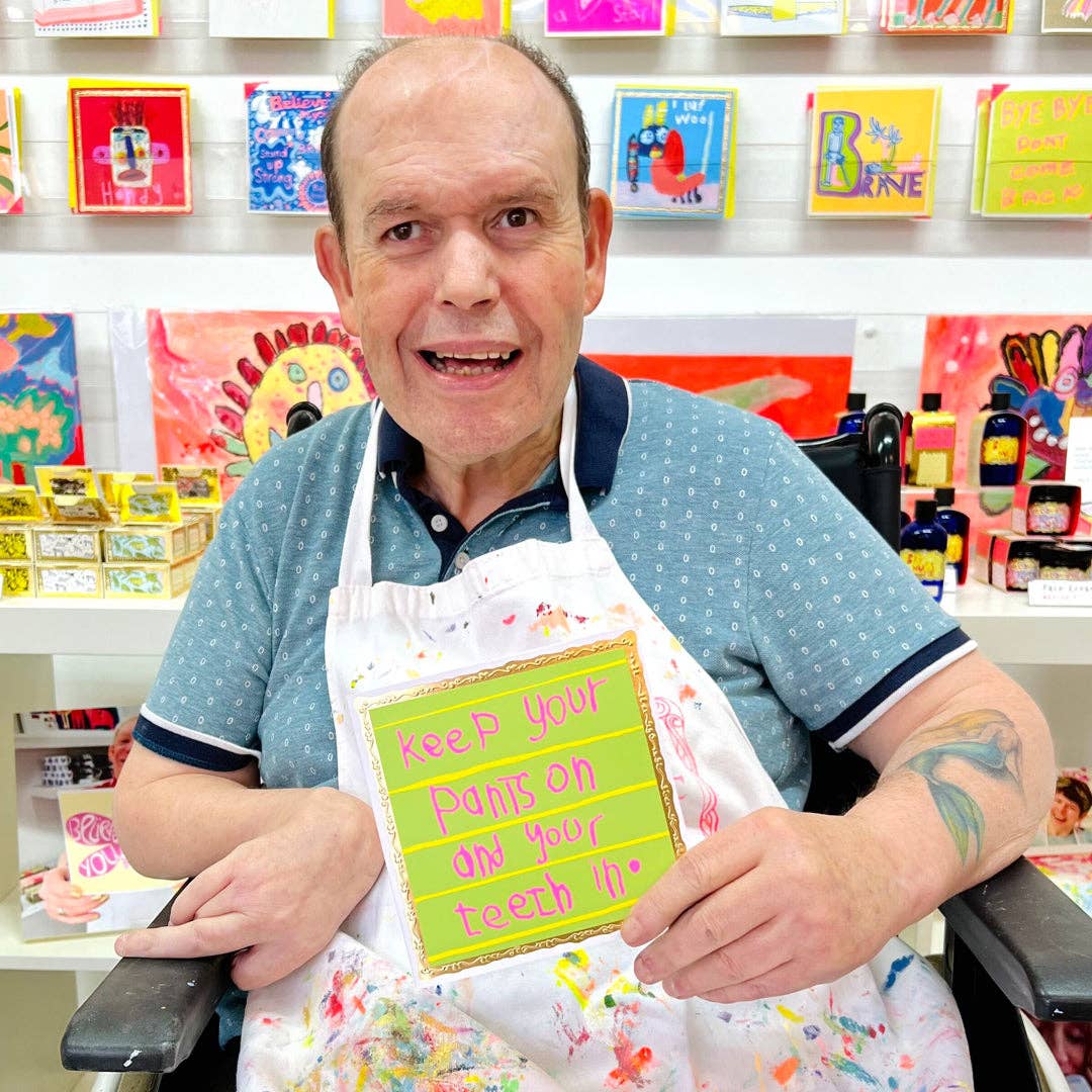 Man wearing a colorful apron with a humorous message in a store setting
