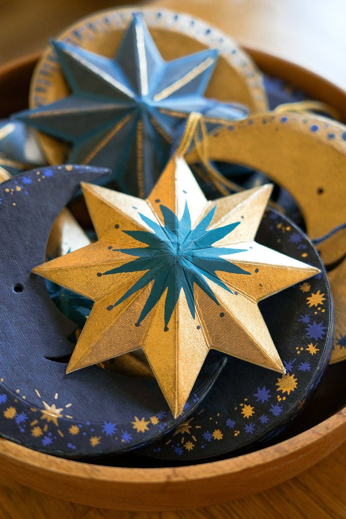 Decorative star-shaped objects with blue and gold colors on a wooden surface.