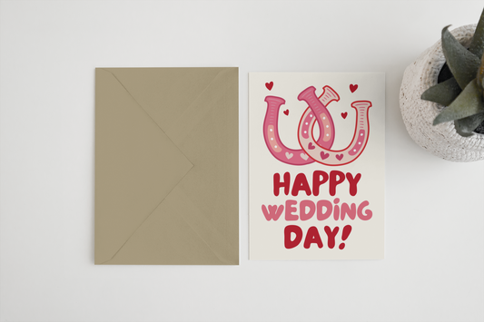Greeting card with pink horseshoe design and 'Happy Wedding Day!' text on a white background.