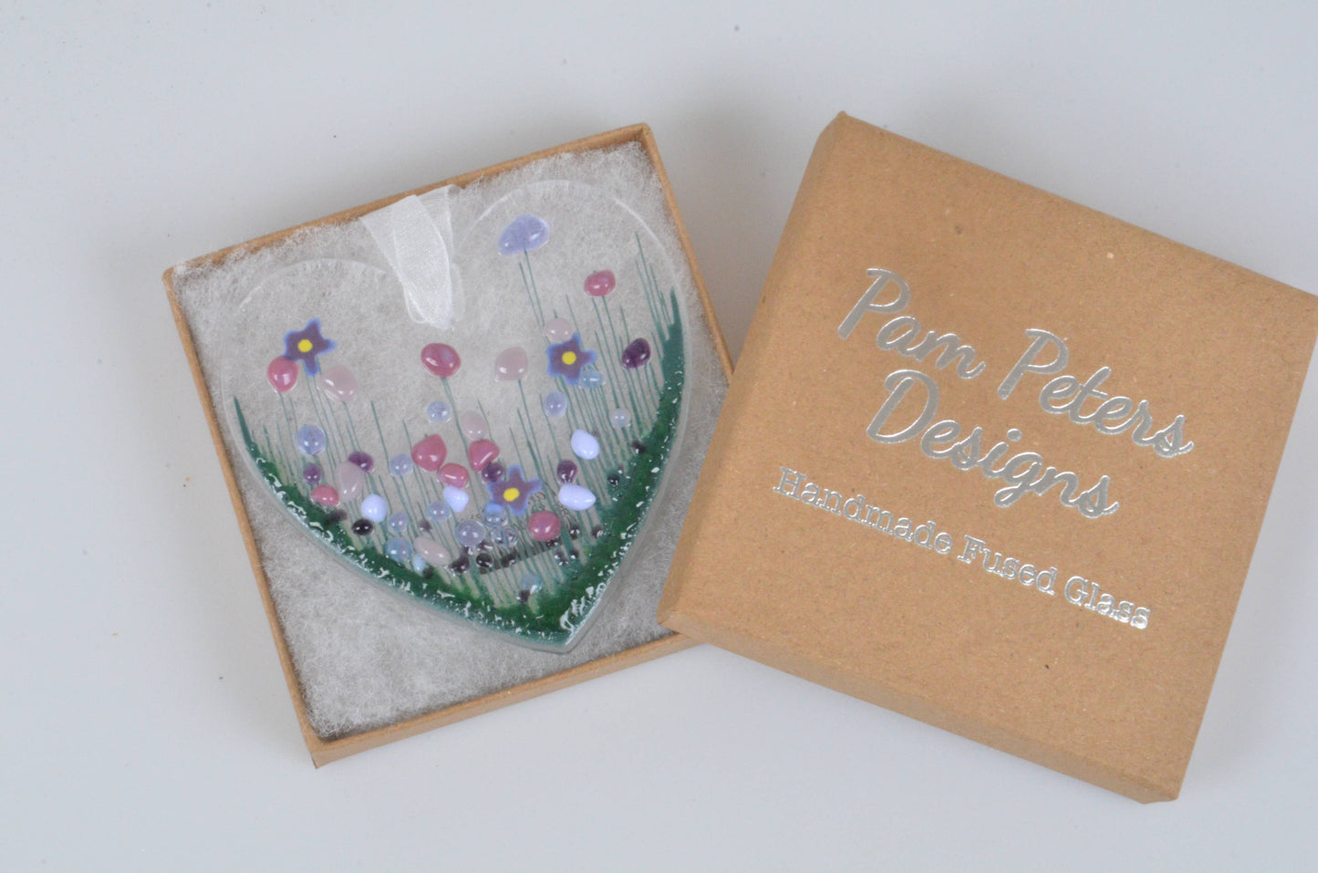 Decorative glass piece with floral design in a 'Pam Peters Designs' box on a white background