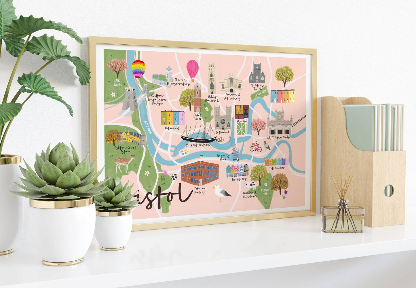 Framed map of Bristol on a shelf with plants and office supplies.