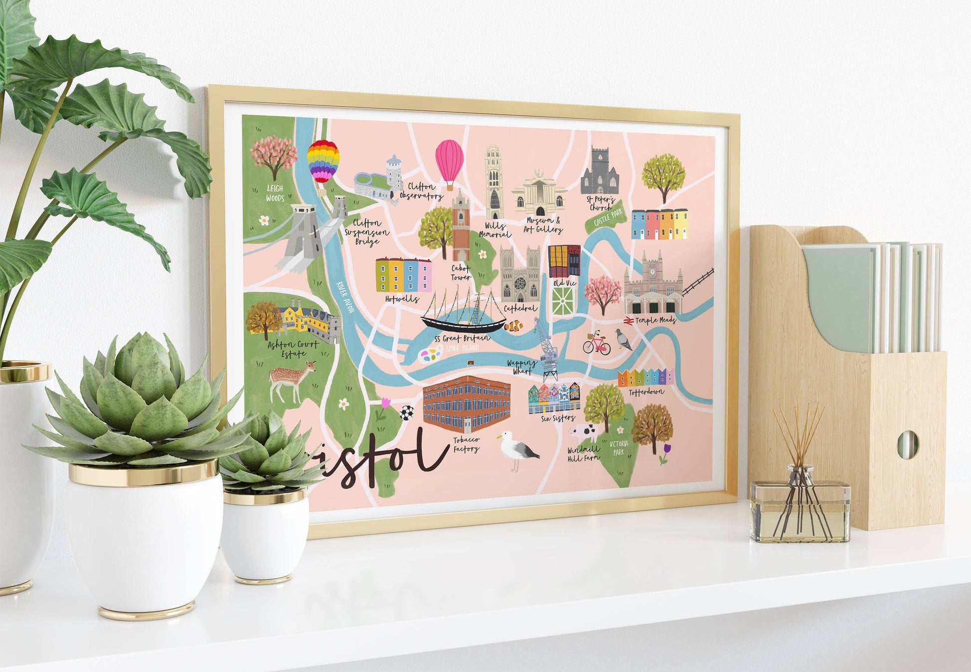 Framed map of Bristol on a shelf with plants and office supplies.