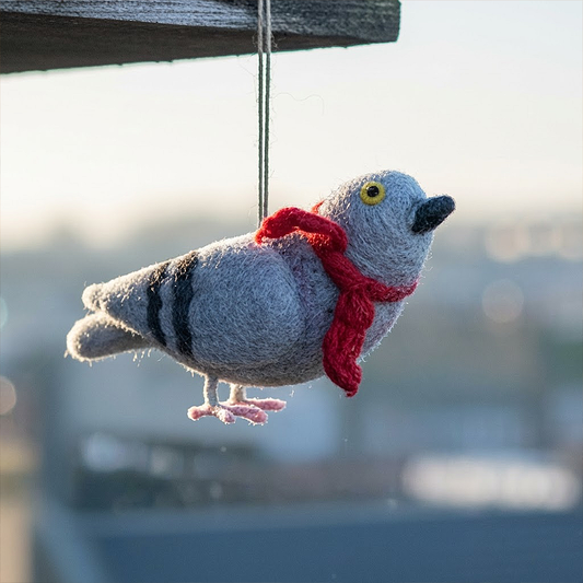 Felted bird ornament with a red scarf hanging against a blurred background