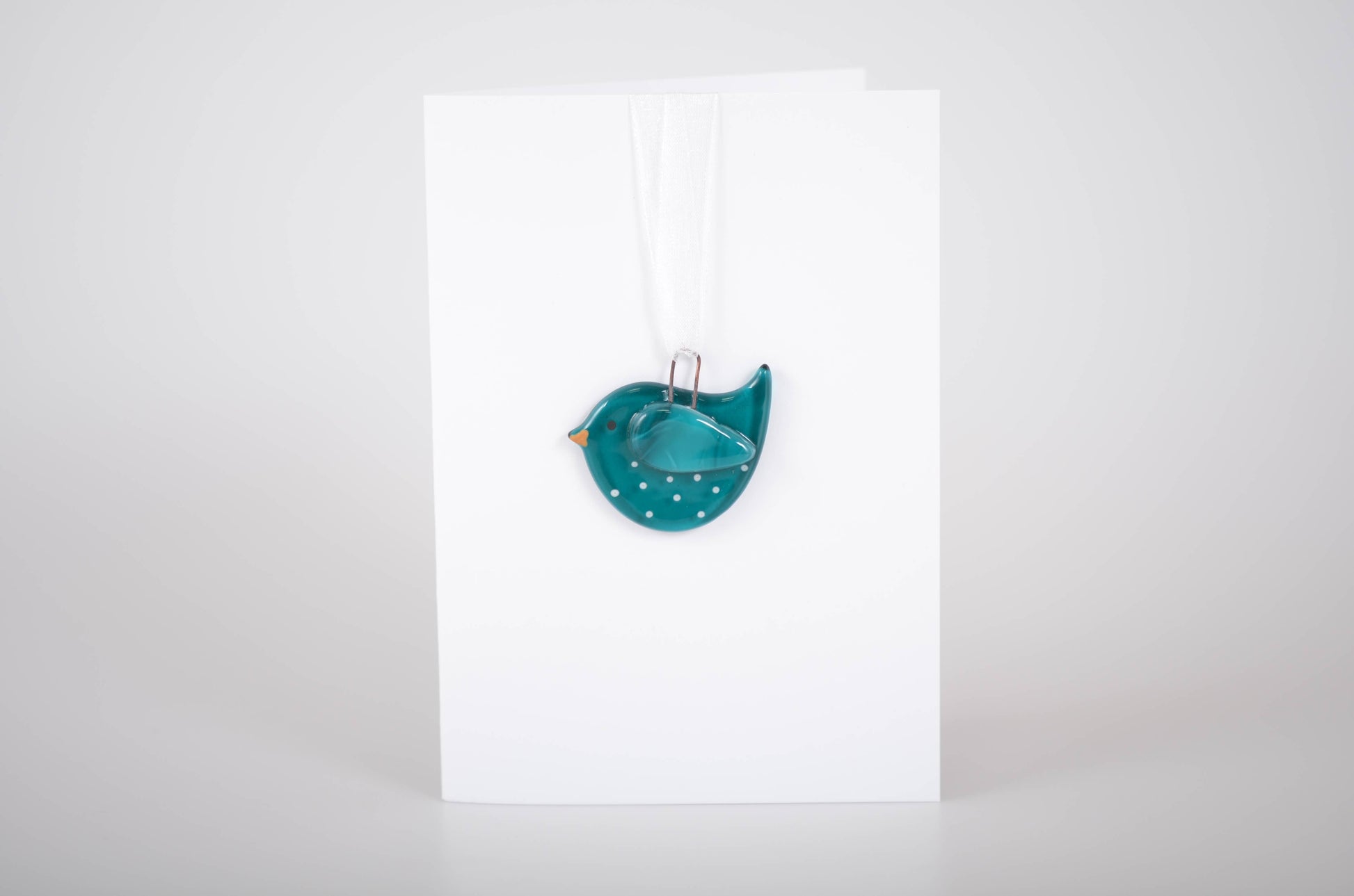 Teal bird-shaped object on a white background