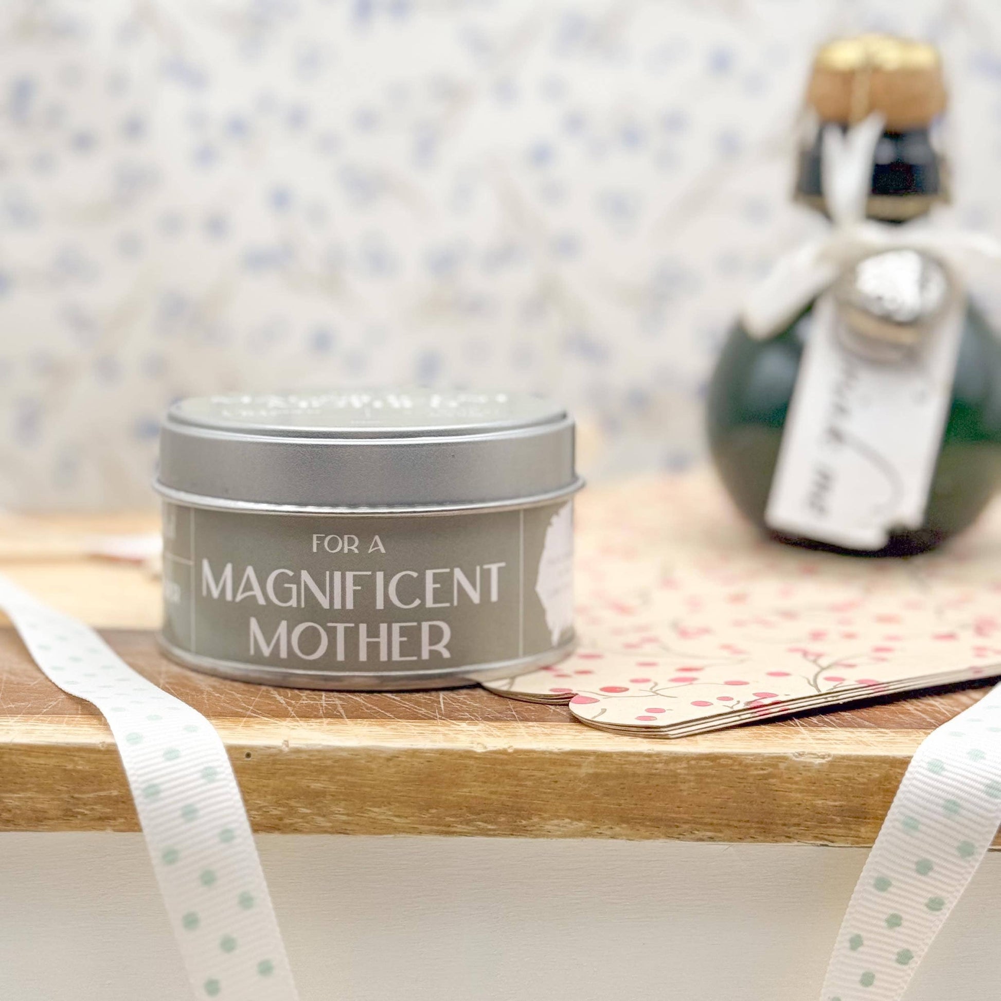 Tin labeled 'For a Magnificent Mother' on a wooden surface with decorative elements.
