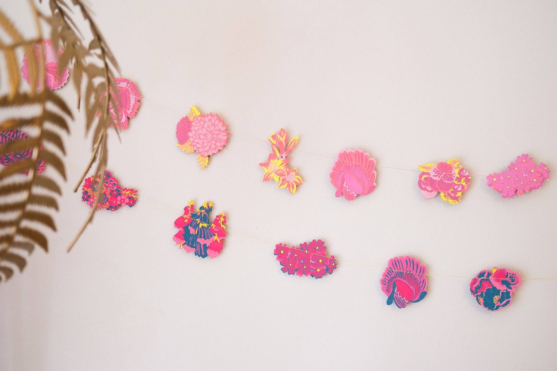 Colorful shell-shaped decorations on a white wall with a leafy branch in the corner.