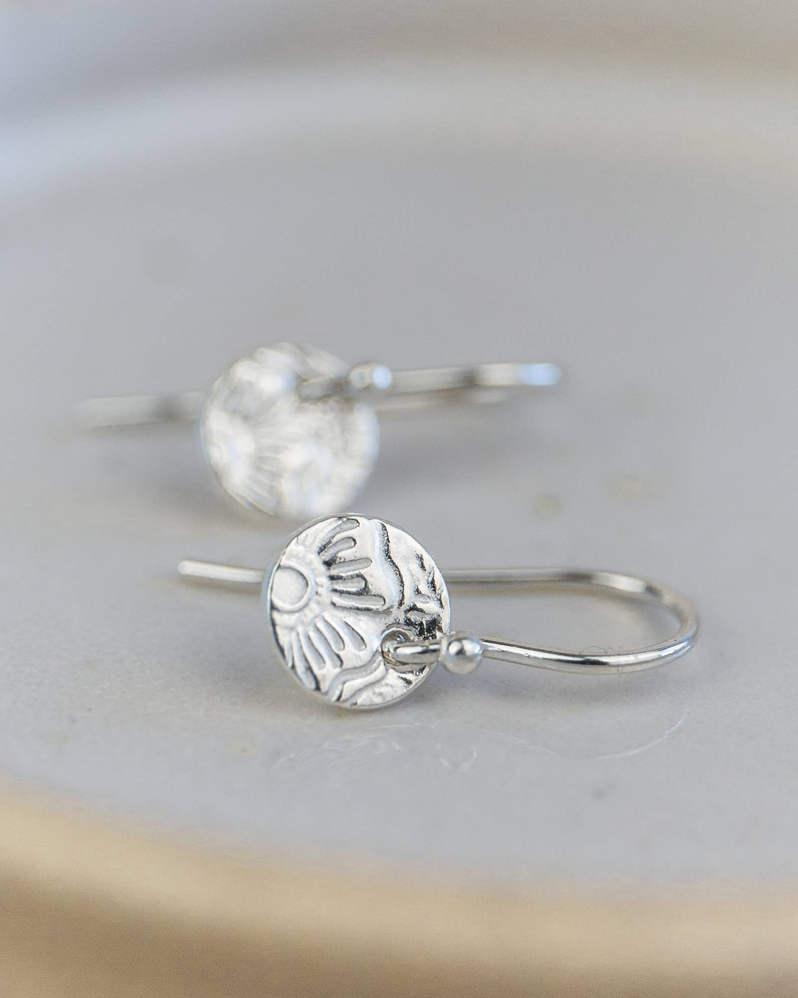 Silver earrings with intricate designs on a light gray background