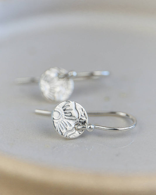 Silver earrings with intricate designs on a light gray background