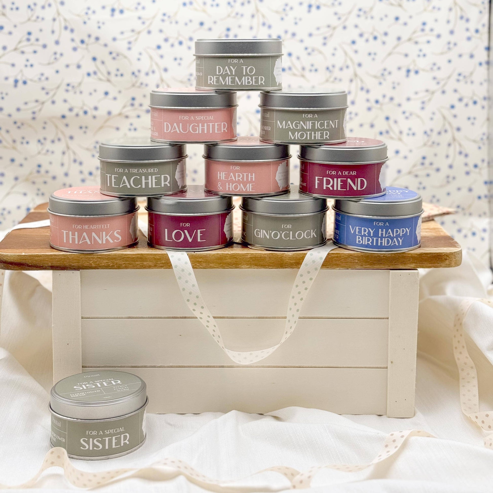Stack of small tin containers with various messages on a wooden stand against a patterned wall.