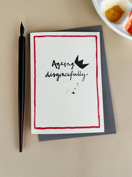Ageing disgracefully in ink with a toppling crown on a cream card with red line around edge.