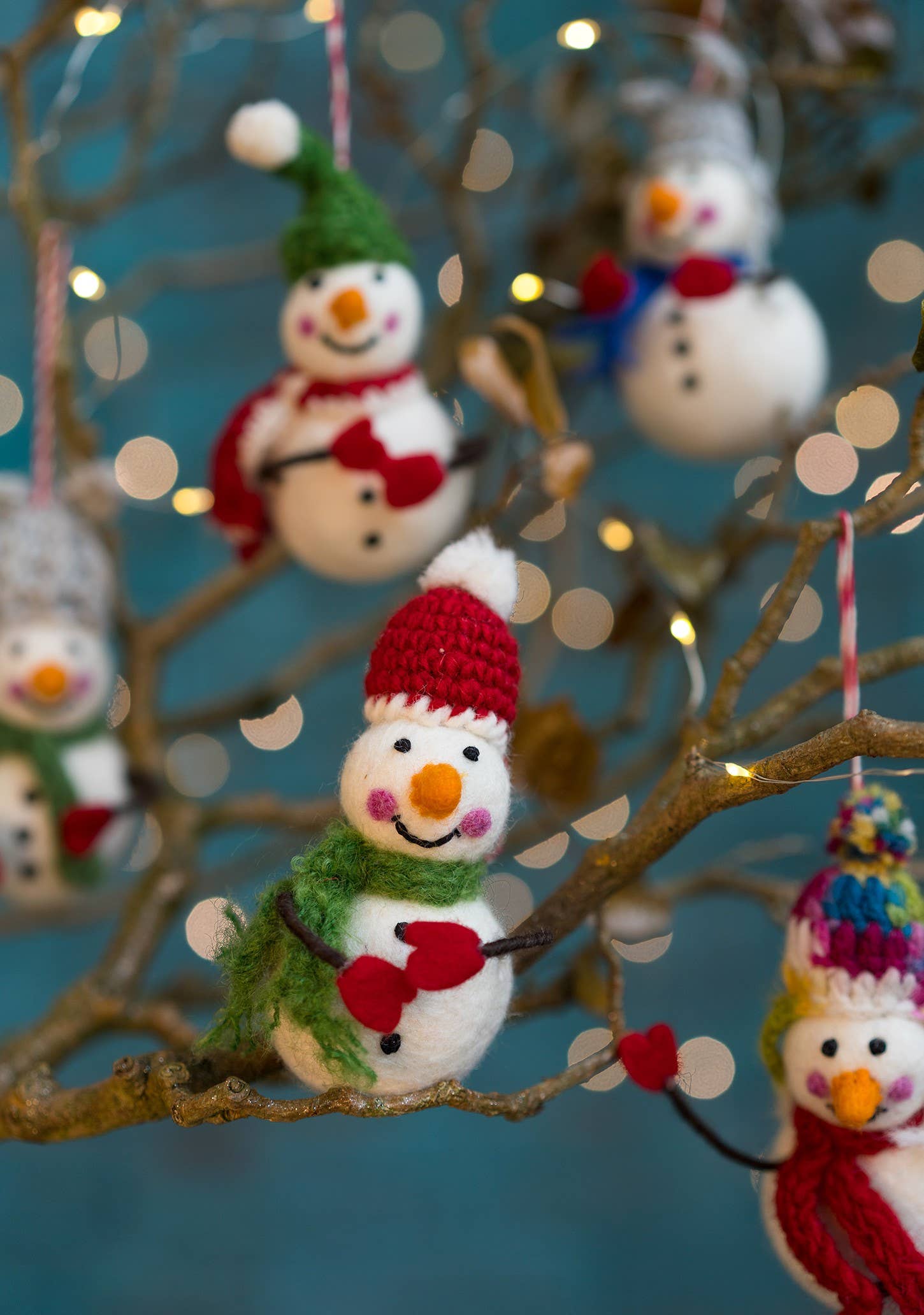 Felted snowman with colourful hat, scarf and bendy arms with mittens on.