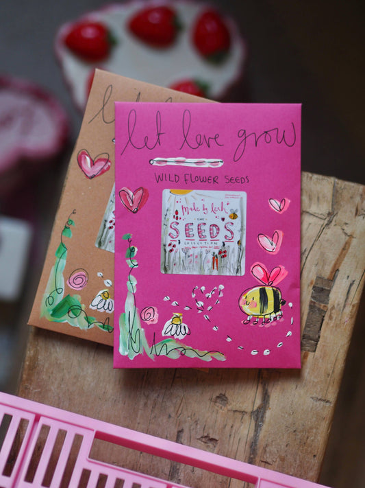 Pink box of wildflower seeds with decorative elements on a wooden surface